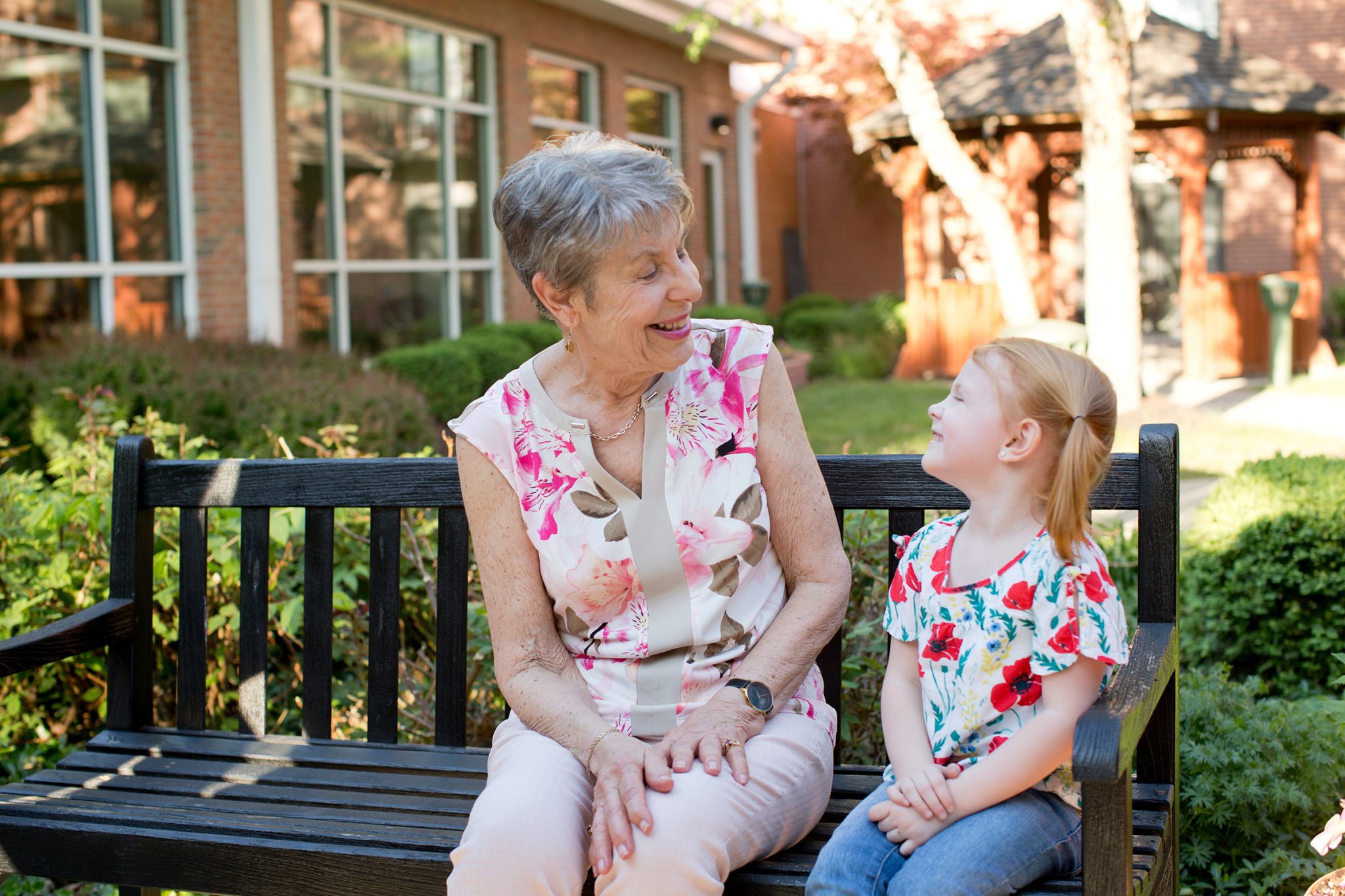 A women and child sitting on a park bench at Kingswood Senior Living Located in Kansas City, MO.