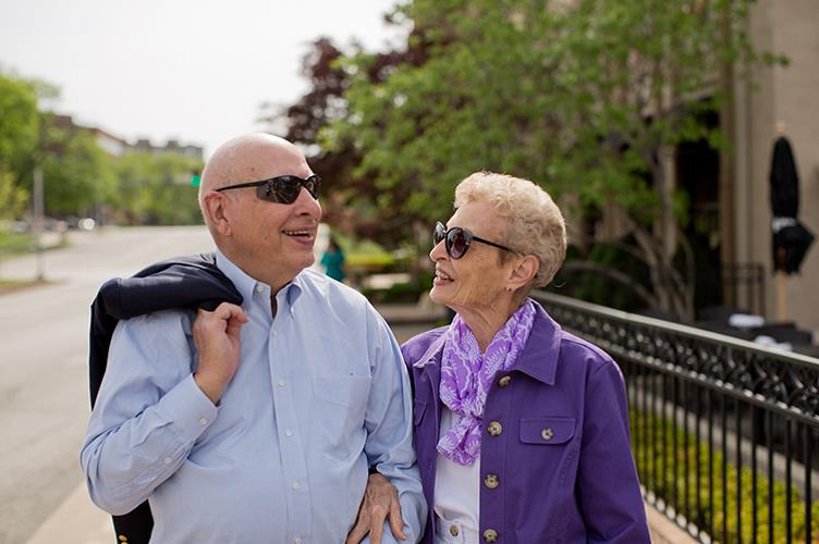 A couple walking down the sidewalk at Kingswood Senior Living Located in Kansas City, MO.