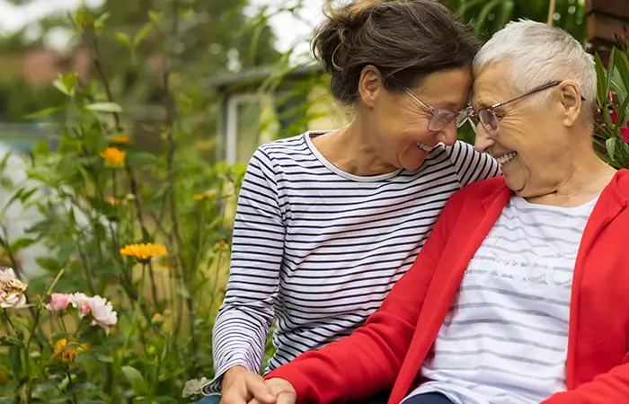 Two women sitting and smiling with flowers